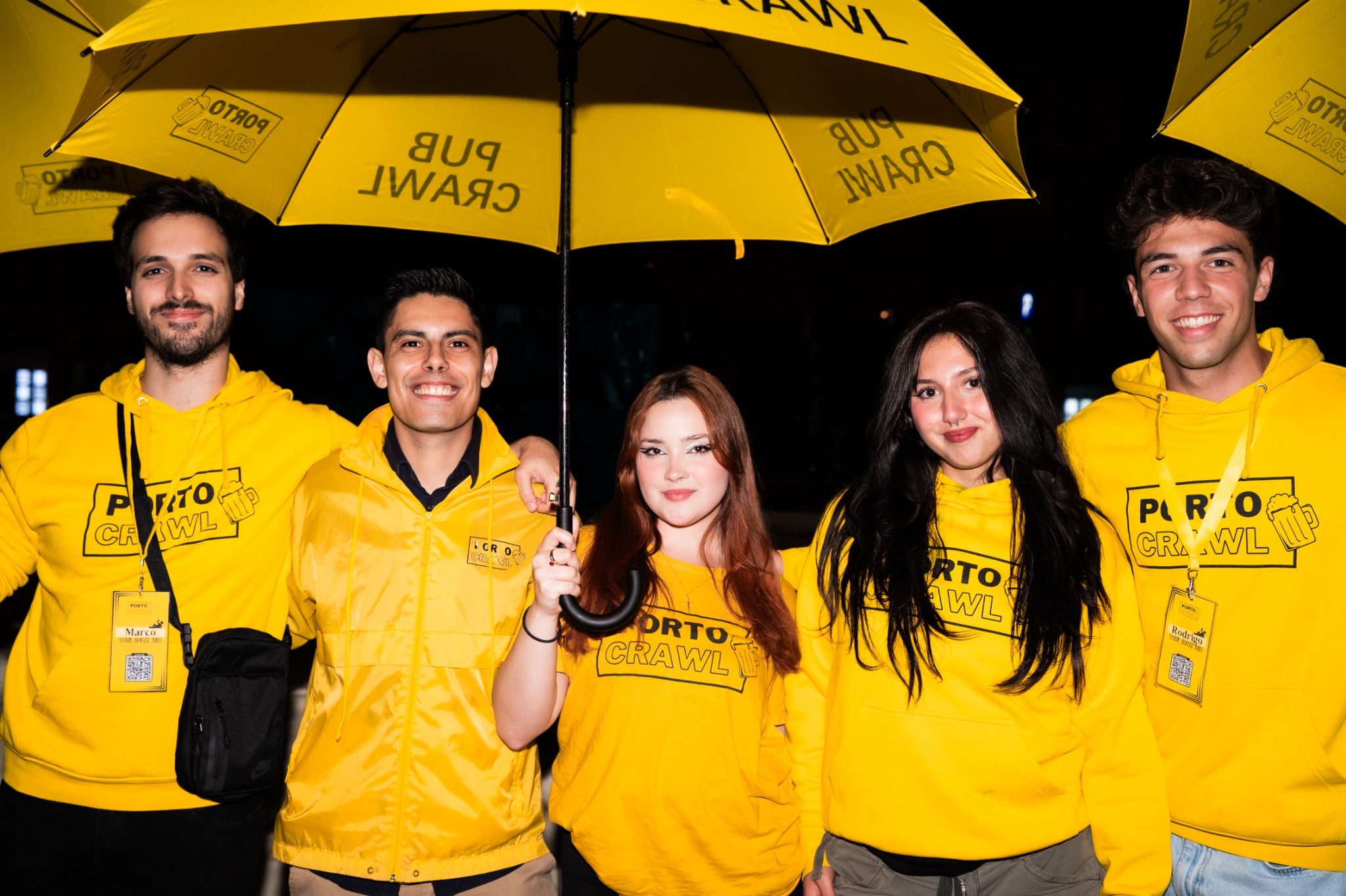 Porto Crawl team in yellow hoodies under yellow pub crawl umbrellas